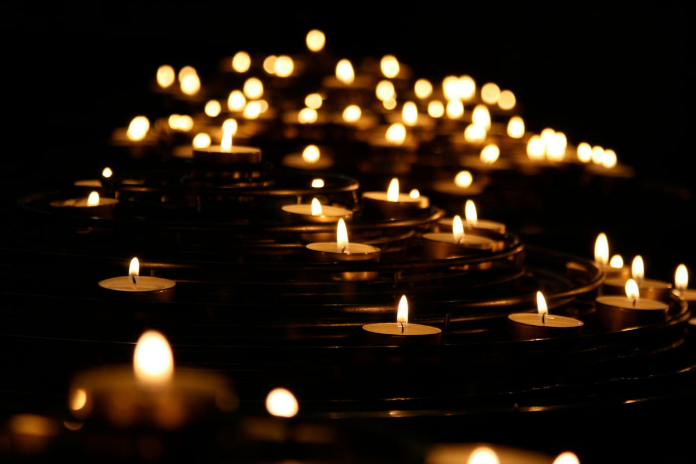 Rows of lit votive candles in a dark church