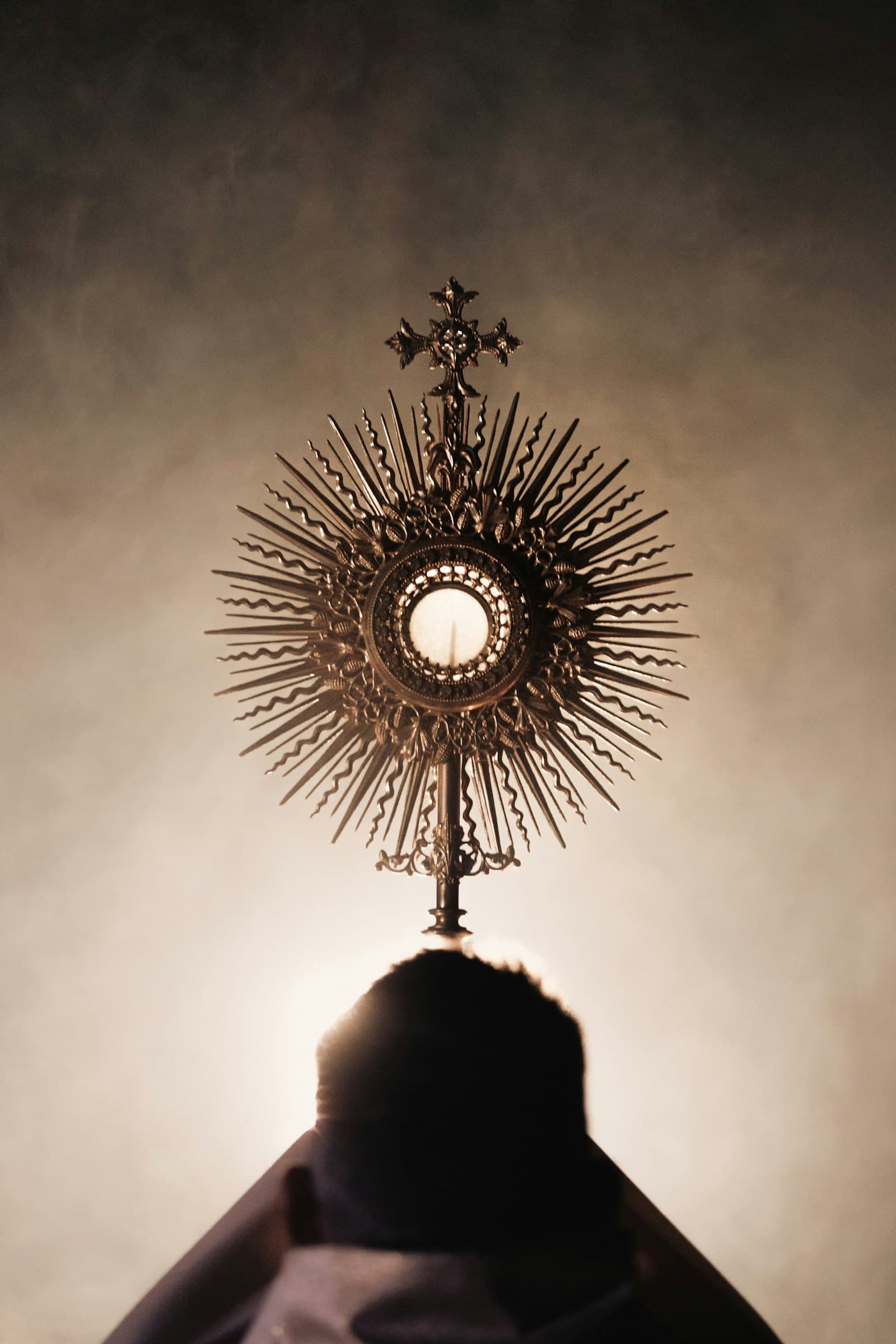 A golden monstrance held up against soft light